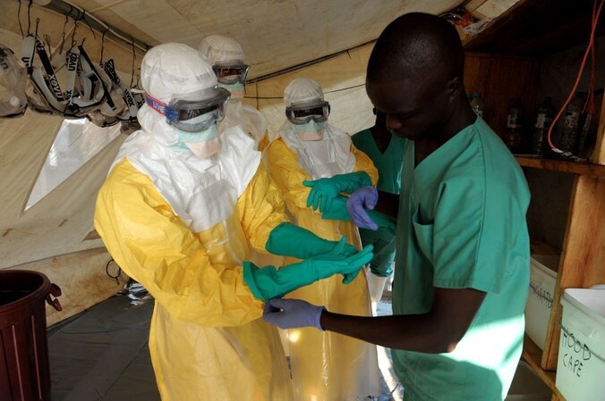 Artsen worden in geïsoleerde kleding geholpen voor ze ebola-patiënten behandelen