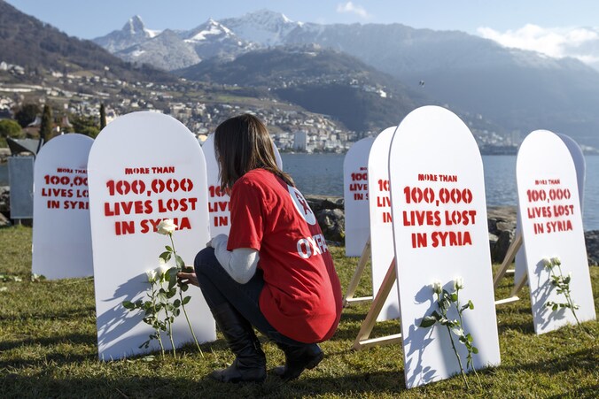 Een Oxfam-medewerker legt witte rozen bij symbolische grafstenen voor de slachtoffers in Syrië.