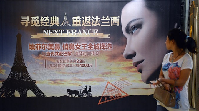 Een Chinese vrouw bekijkt een advertentie voor de zogenaamde 'Eiffeltorenneus'.