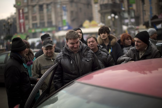 Janoekovitsj-opposanten luisteren naar zijn persconferentie op een autoradio in Kiev.