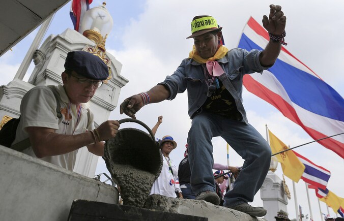 Demonstranten gieten cement in een gat om het kantoor van premier Yingluck Shinawatra af te grendelen.