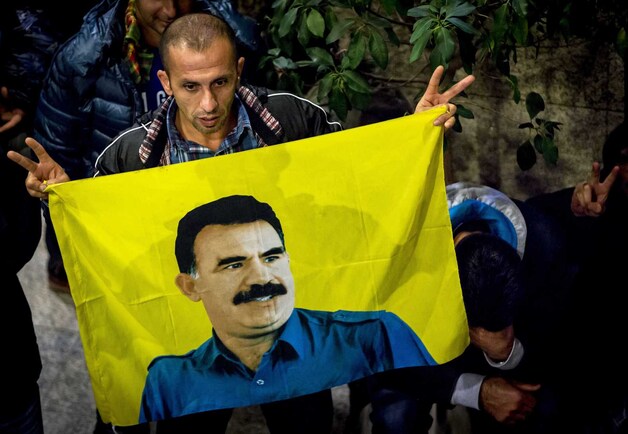 Een Koerdische demonstrant toont een vlag van PKK-leider Abdullah Ocalan in Den Haag.