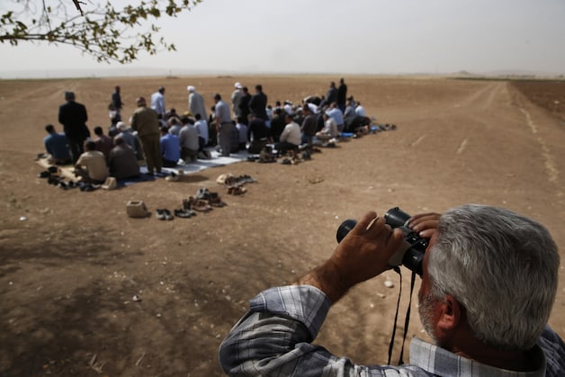 Vanuit de heuvels bij de Turkse grens wordt de strijd met verrekijkers gevolgd.