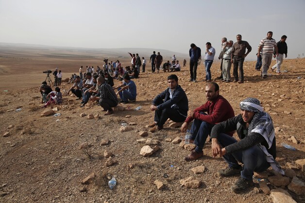 Mensen troepen samen op een heuveltop vlak buiten Suruc aan de Turks-Syrische grens om de gevechten tussen de Syrische Koerden en de militanten van de Islamitische Staat te volgen.