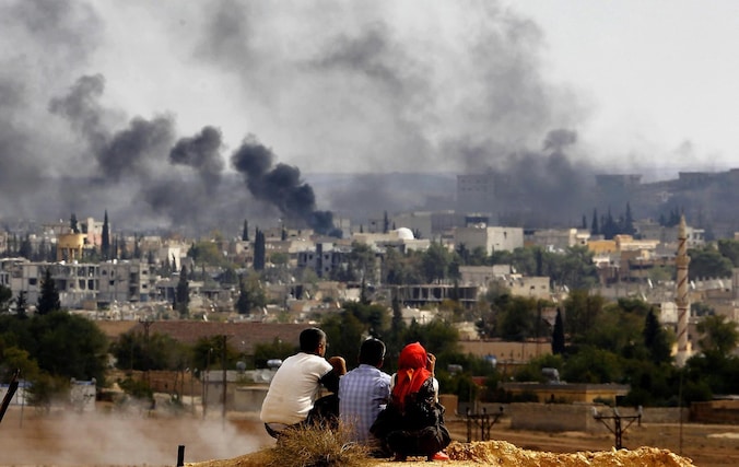 Gevluchte Koerden kijken bij de Turkse grens naar de rook boven Kobani