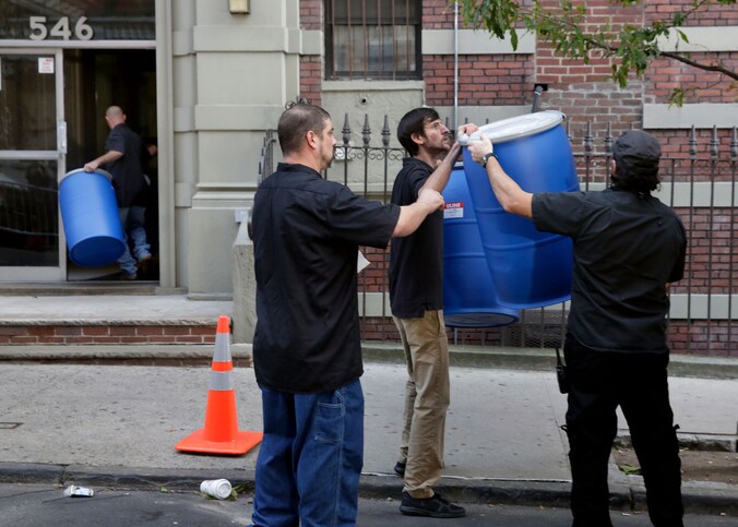 In hermetisch afgesloten tonnen wordt de inhoud van het appartement van de besmette arts in New York afgevoerd.