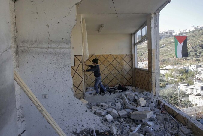 Een jongen staat in de ruïne van het huis van Abdel-Rahman Shaloudi, de Palestijn die vorige maand een aanslag pleegde in Jeruzalem.