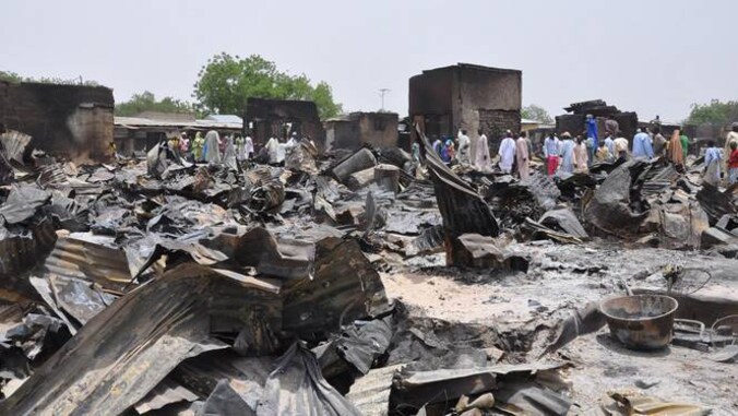 Mensen lopen tussen de door Boko Haram verbande huizen in Gambaru, Nigeria.
