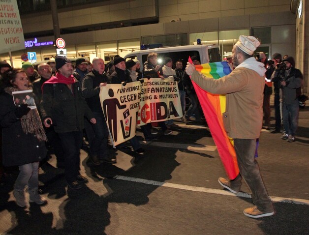 Een tegendemonstrant kon door het politiecordon breken en toonde de Pegida-demonstranten een regenboogvlag.