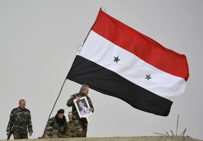 Strijders loyaal aan president Bashar al-Assad tonen zijn portret in de zuidelijke Syrische stad Deir-al-Adas.