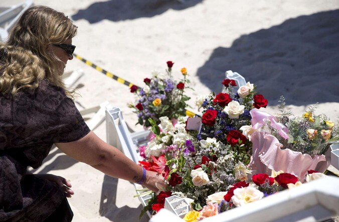 Een vrouw legt bloemen op het strand waar gisteren de aanslag plaatsvond.
