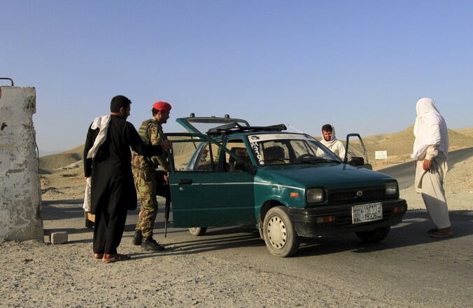 Afghaanse soldaten doorzoeken een voertuig.