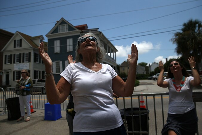In Charleston bidden vrouwen op straat, voor de kerk waar Dyllan Roof negen mensen doodschoot.