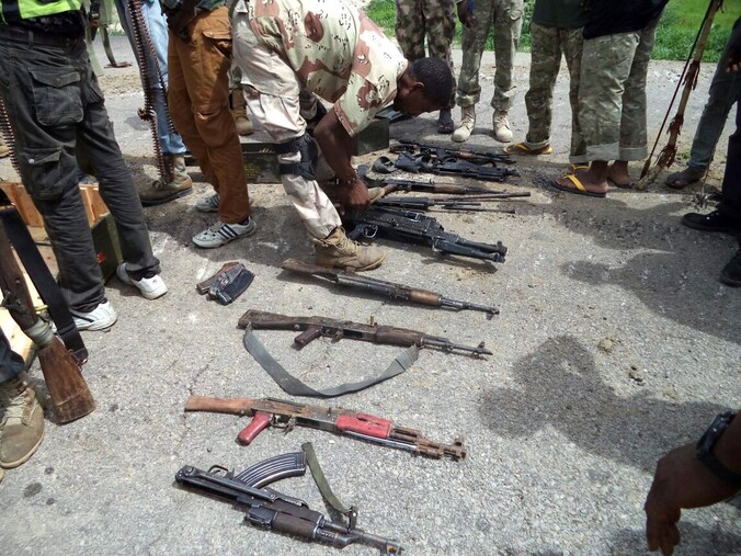 Een soldaat van het Nigeriaanse leger neemt wapens van Boko Haram-strijders in beslag.