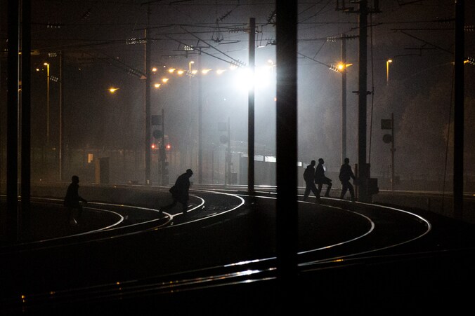 Vluchtelingen wandelen over de treinsporen in de buurt van de Eurotunnel in Calais