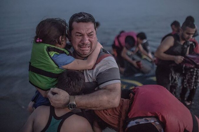 De Syrische vader omarmt zijn zoon en dochter wanneer het gezin om halfvijf 's ochtends een strand op het Griekse eiland Kos bereikt.