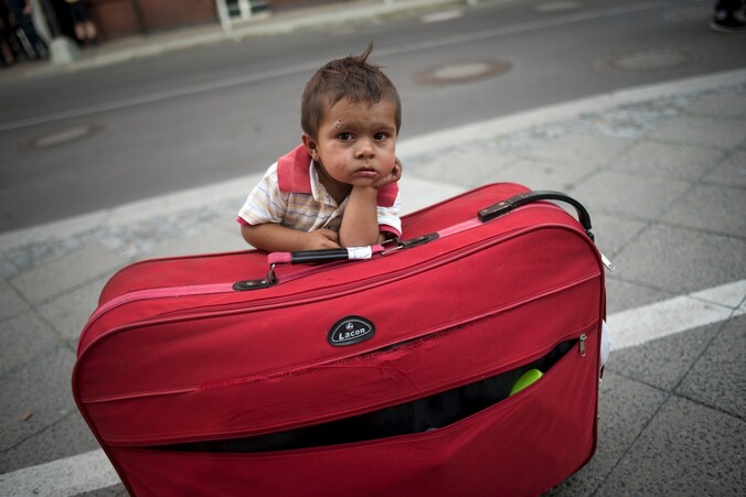 Een jongen wacht bij de bagage op zijn ouders in het treinstation van Berlijn.