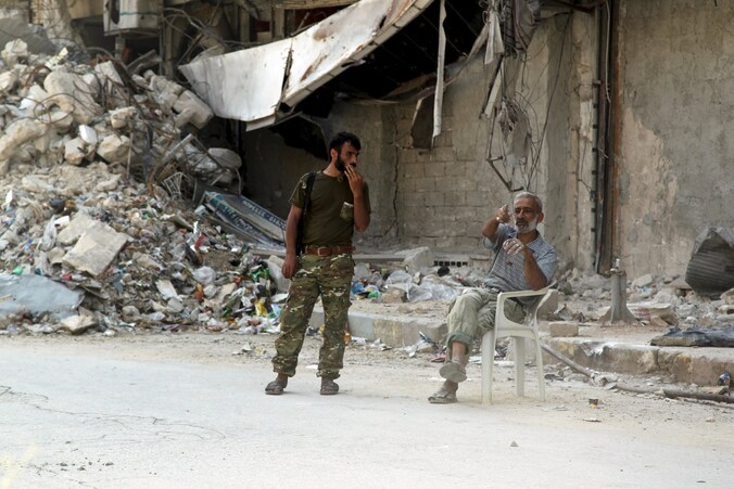 Een militair van het Syrische leger in gesprek met een inwoner van een verwoeste straat in Aleppo.