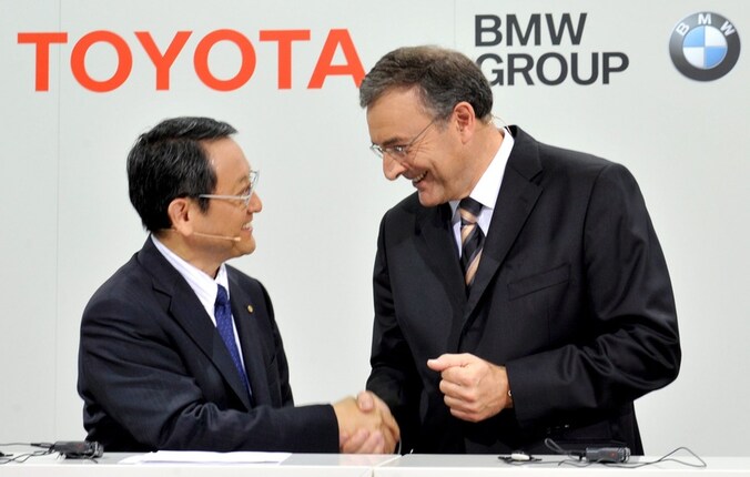 Akio Toyoda, topman van Toyota, schudt BMW-topman Norbert Reithofer (r.) de hand.