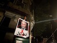 Een betoger toont een foto van Shafiq met een rood kruis over.