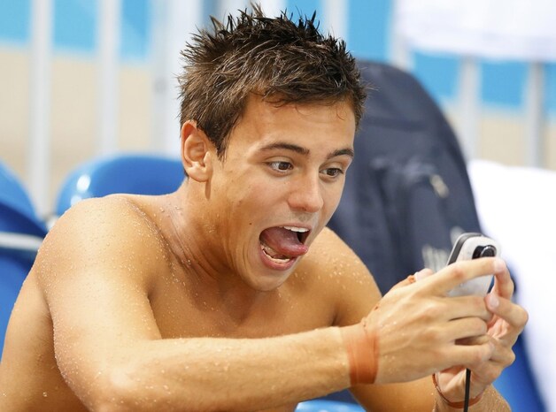 De Britse schoonspringer Tom Daley gaat helemaal op in zijn smartphone tijdens de training voor de Spelen.