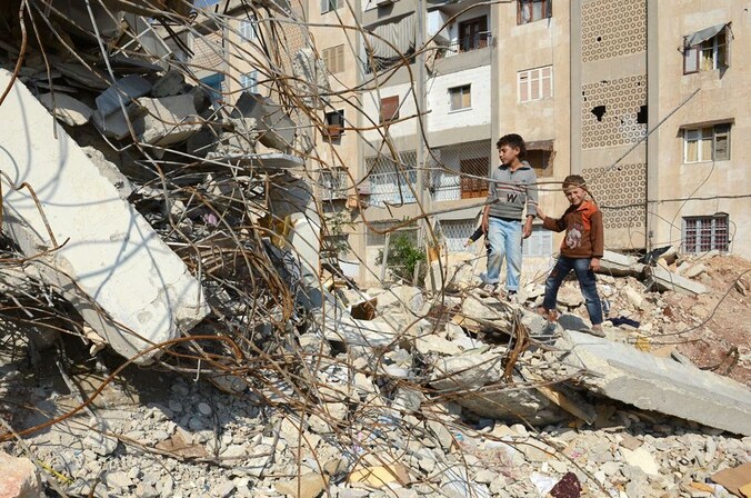 Kinderen poseren bij een vernield huis in Aleppo.