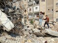Kinderen poseren bij een vernield huis in Aleppo.