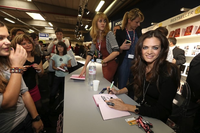 Astrid Bryan signeert haar boek op de boekenbeurs.