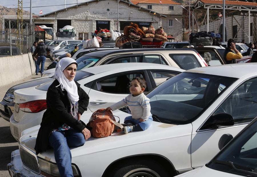 Een Syrische moeder wacht om de grens met Libanon over te steken.