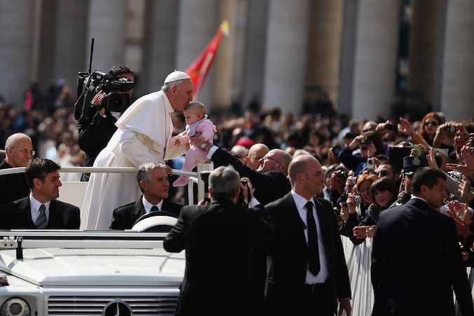 Paus Franciscus kust woensdag een baby tijdens een ritje over het Sint Pieterplein.