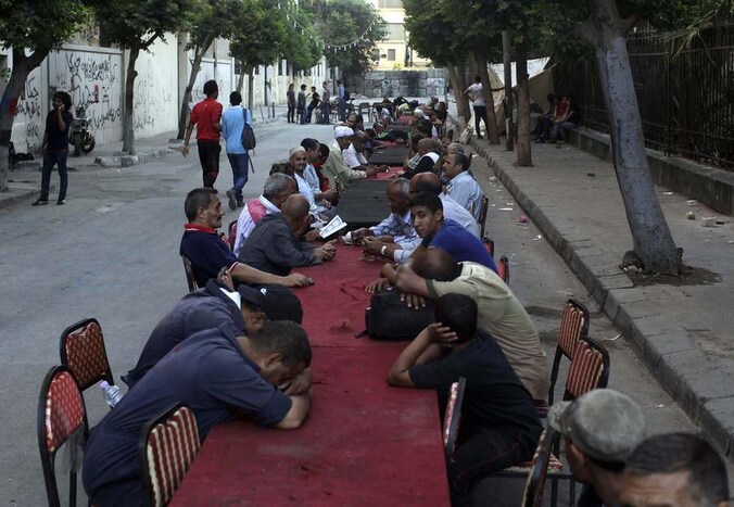 Egyptische moslims zitten in de buurt van het Tahrirplein in Cairo aan lange tafels te wachten tot ze mogen eten volgens de Ramadan.