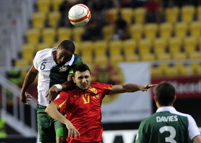 Ashley Williams met Wales in een luchtduel met de Macedoniër Jovan Kostovski, spits van OH Leuven.