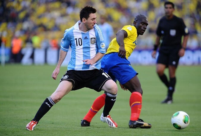 Lionel Messi (Argentinië) in duel met Segundo Castillo van Ecuador.