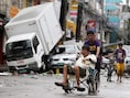 Een Filipijnse man in rolstoel wordt voortgeduwd door de straten van de verwoeste stad Tacloban op de Filipijnen.