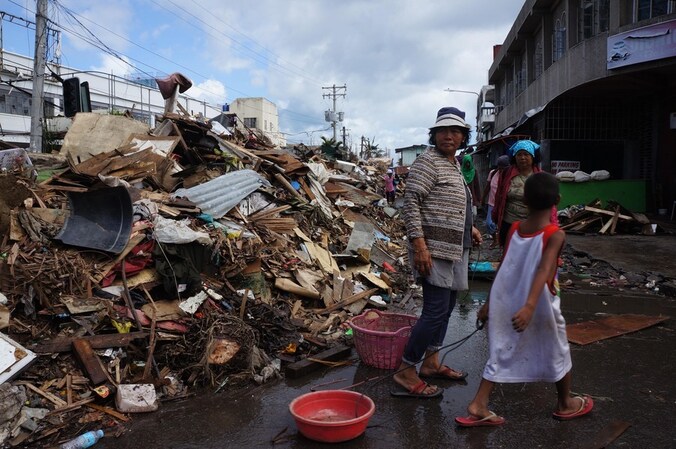 Inwoners van Tacloban lopen langs de puinhopen van tyfoon Haiyan.