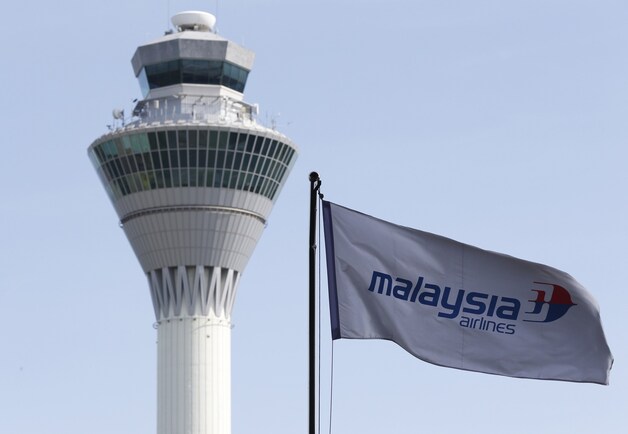 Een vlag van Malaysia Airlines wappert voor de luchtverkeerstoren van het vliegveld van Kuala Lumpur.