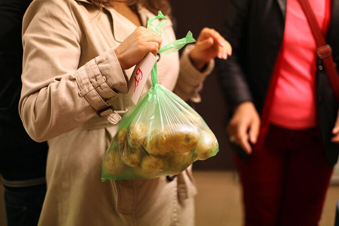 Een vrouw krijgt aardappelen tijdens een voedselbedeling van Caritas.