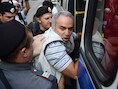 Kasparov wordt een politiebusje ingeduwd.
