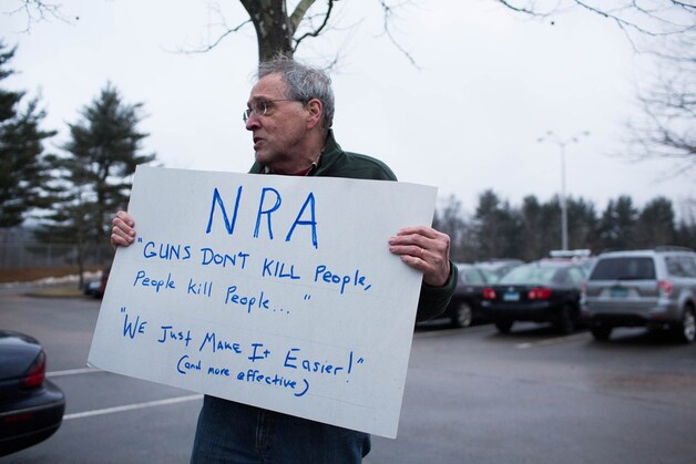Een actievoerder neemt de NRA op de korrel aan de Sandy Hook-school in Newtown.