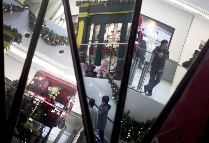 Shoppers zijn te zien in de spiegels van een winkelcentrum in Peking.