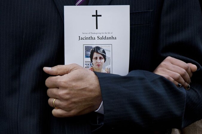 Haar man Benedict Barboza houdt het doodsprentje van zijn overleden vrouw vast tijdens de herdenkingsplechtigheid in Westminster Cathedral.