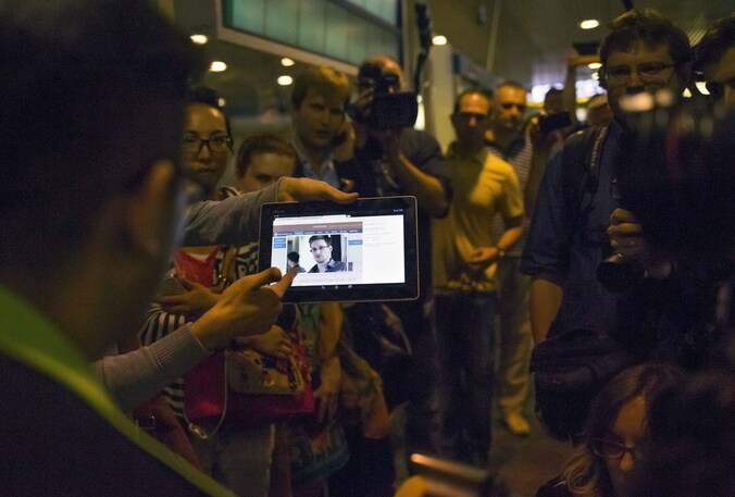 Een journalist houdt een tablet vast met daarop een foto van Edward Snowden op het vliegveld in Moskou.