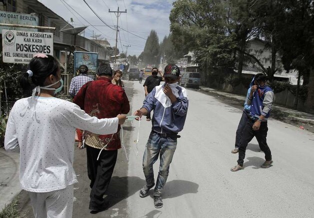Een dokter deelt maskers uit aan mensen die in de buurt van Sinabung wonen.