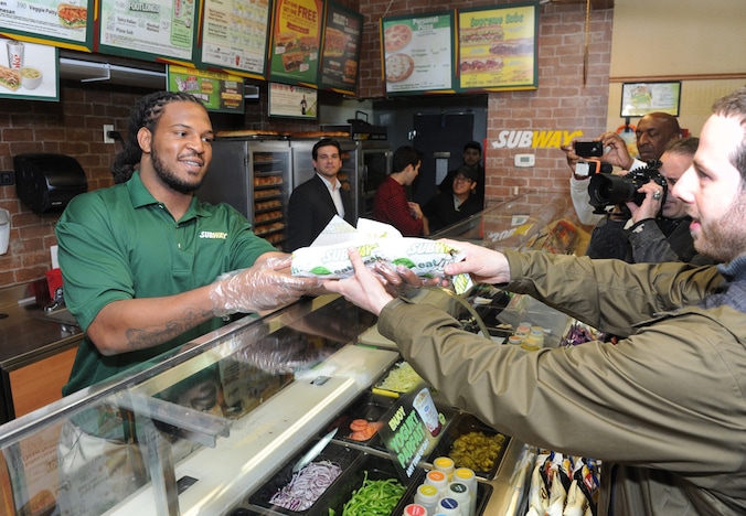 Een man krijgt een broodje bij Subway.