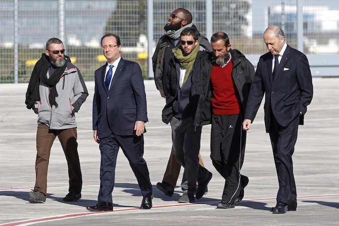 De Franse president en dienst minister van Buitenlandse Zaken samen met de vier vrijgelaten gijzelaars op de militaire luchthaven Villacoublay, buiten Parijs.