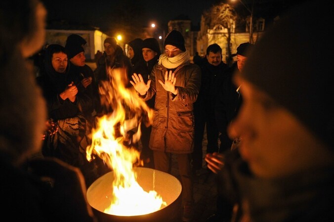 Manifestanten warmen zich op het Mikhaylivskaplein in Kiev.