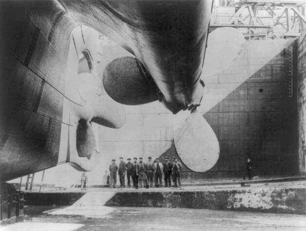Arbeiders poseren bij de gigantische schroef van de Titanic.