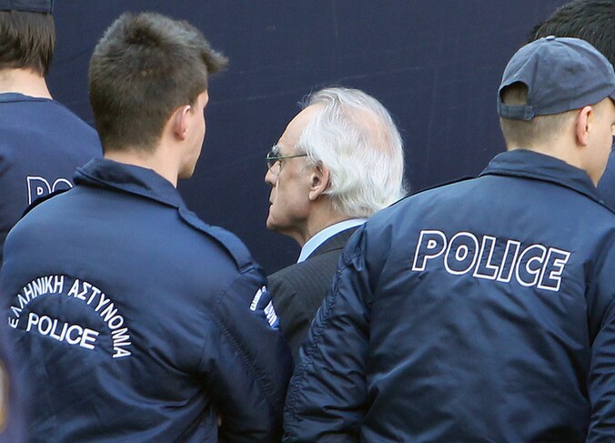 Tsochatzopoulos begeleid door agenten aan het gerechtsgebouw in Athene.