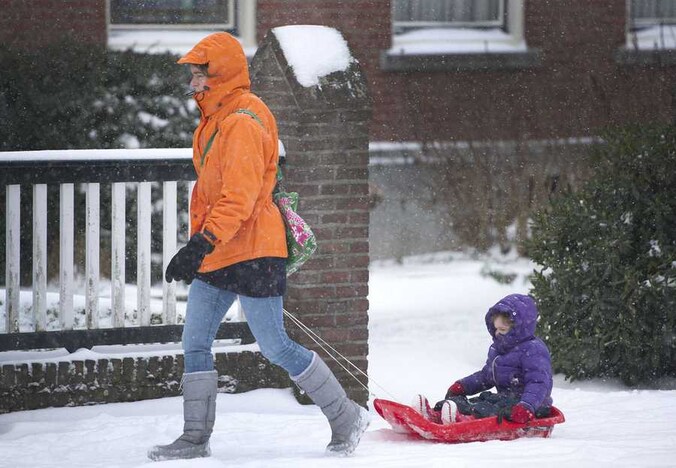 Een vrouw met een slee baant zich een weg door de sneeuw in Heerlen.