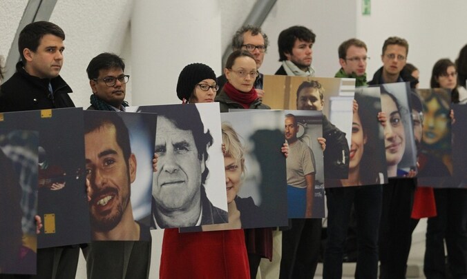 Greenpeace-activisten houden foto's vast van de gearresteerde 'Arctic 30'.
